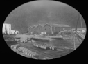 Image of Large frame buildings. Barrels on dock